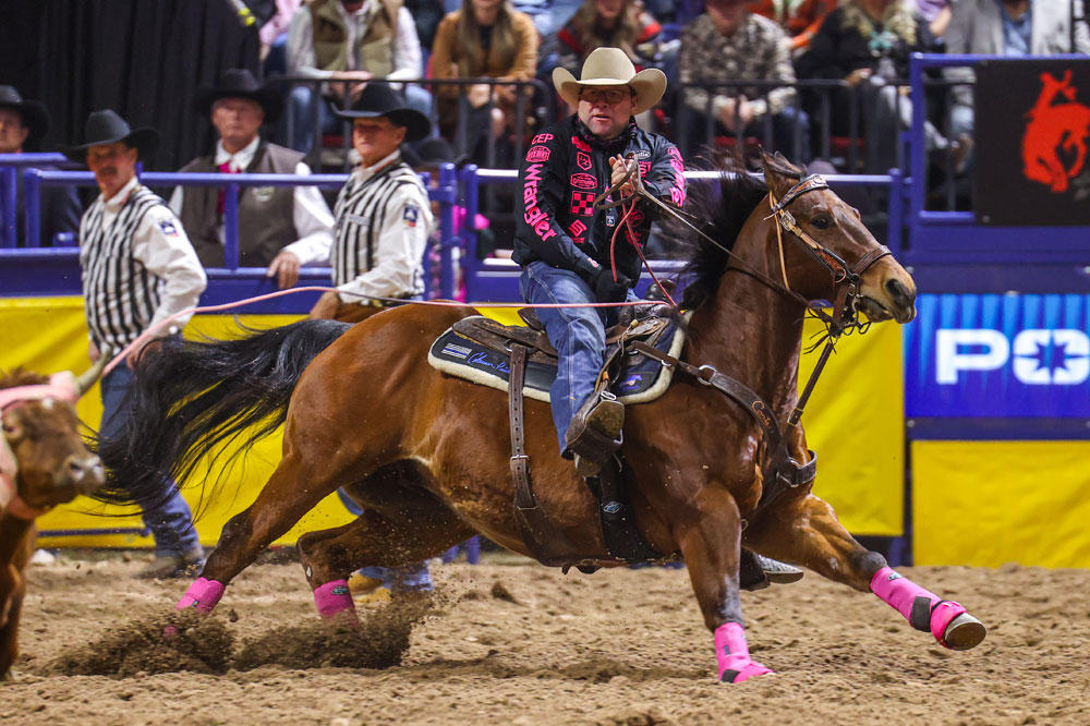 A cowboy riding hose at a rodeo.